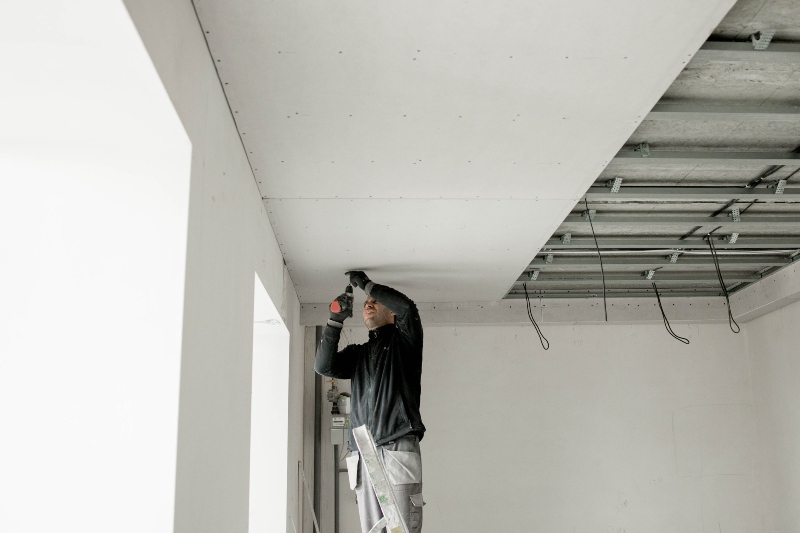the worker attaches plasterboard on metal frame. installation of ceiling.