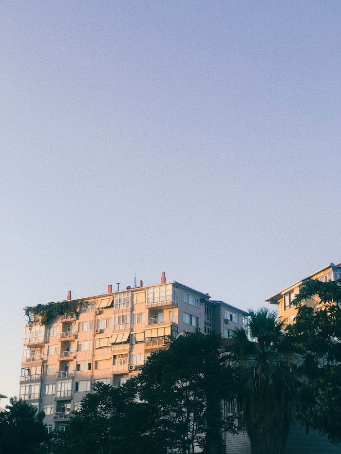 High-rise residential building with trees under a clear sky, captured at twilight.
