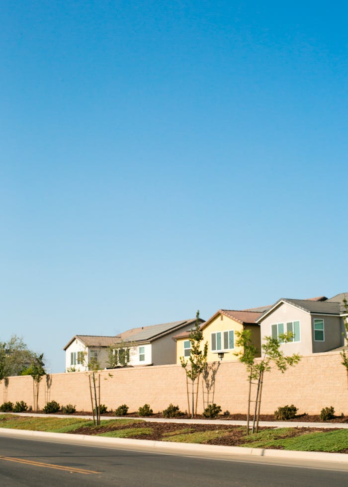 Modern suburban houses bordered by a tall wall under a clear blue sky, capturing peaceful urban living.